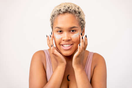 African girl with short dyed blond hair and toothy smile having undereye mask