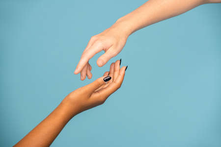 Hands of girls of Caucasian and African ethnicities stretching to each other