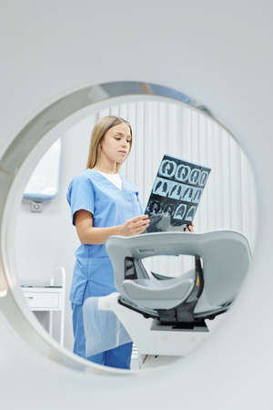 Young radiologist in uniform looking at x-ray image of patient head and brainの写真素材