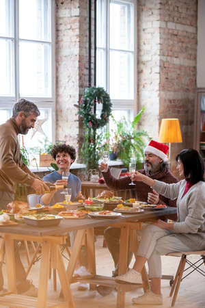 Two couples cheering up with flutes of champagne over festive table on xmasの写真素材