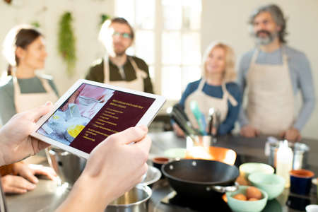 Hands of male cooking coach with tablet looking through online recipesの写真素材