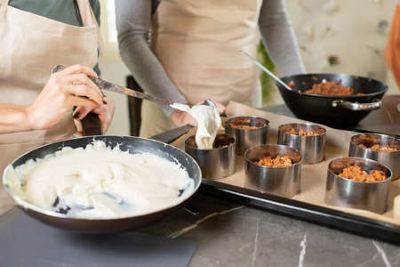 Hands of young woman putting dough into metallic forms with fried minced meatの写真素材