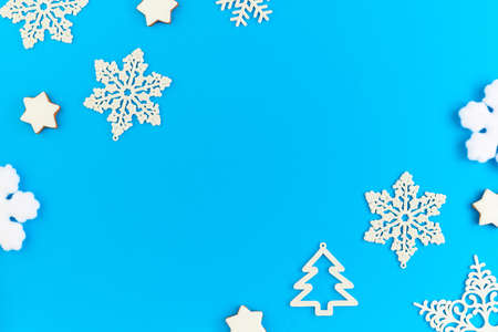 Flat layout of white decorative snowflakes and firtrees surrounding copyspace