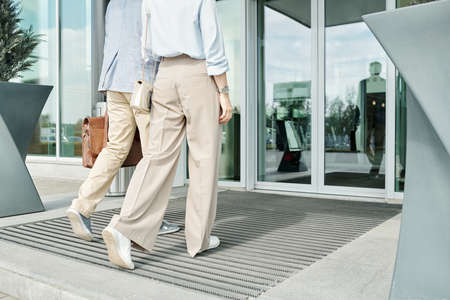 Back view of young couple in casualwear walking towards door of auto center