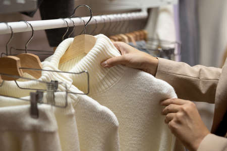 Hands of young female customer looking through new assortment of casualwear