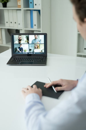 Several colleagues on laptop display looking at businessman sitting by desk