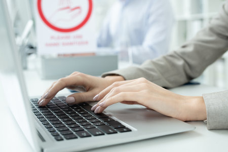 Hands of young contemporary businesswoman in formalwear pressing laptop keysの写真素材
