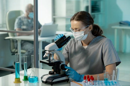 Young contemporary female scientist studying chemical samples in microscopeの写真素材