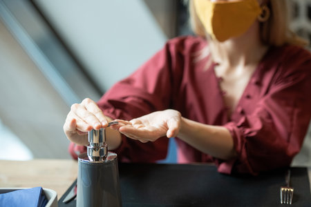 Hands of young elegant woman pressing dispenser of plastic jar with sanitizerの写真素材