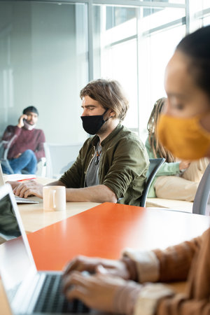 Young businessman in protective mask and casualwear pressing keypad buttonsの写真素材
