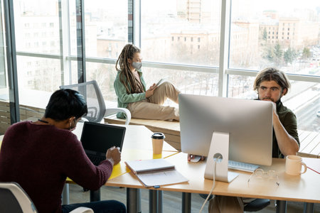 Young businessman looking at computer screen while his male colleague networkingの写真素材