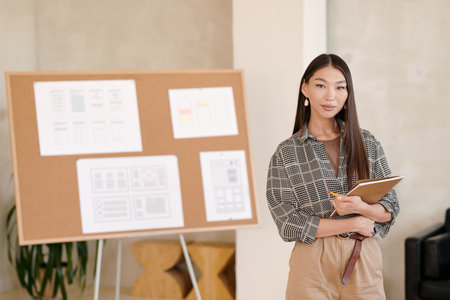 Young brunette businesswoman with long hair holding notebook and pencilの写真素材