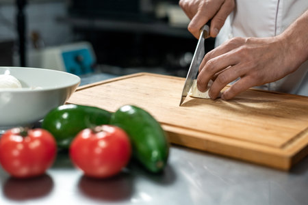 Hands of young male chef of modern restaurant chopping fresh vegetablesの写真素材