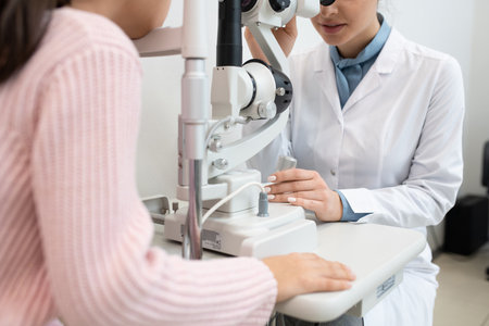 Young female ophthalmologist using medical equipment to check up eyesight