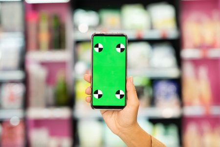 Hand of contemporary shopaholic showing green e-coupon on screen of smartphone