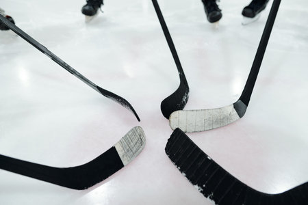 Hockey sticks in the middle of circle made up of players standing on ice rinkの写真素材