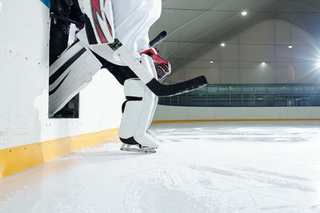 Hockey player in protective helmet, gloves and skates going out from tribuneの写真素材