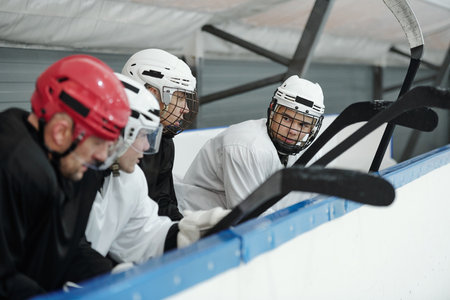 Group of young hockey players in sports uniform and helmets preparing for playの写真素材