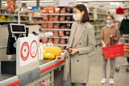 Board on checkout counter announcing requirement about wearing protective masksの写真素材