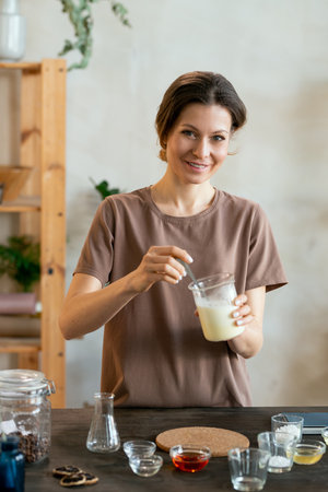 Happy young woman making mixture for natural handmade cosmetic productsの写真素材