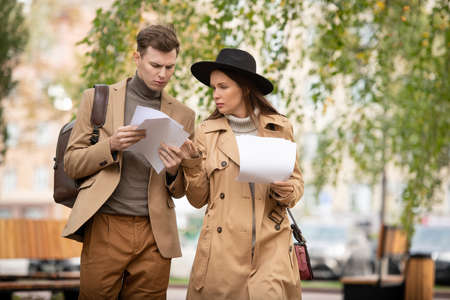 Two young serious economista in smart casualwear looking through papers