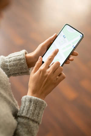 Hands of young female in grey knitted sweater pointing at screen of smartphoneの写真素材