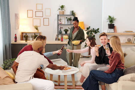 Group of young cheerful intercultural friends in smart casualwear having pizza