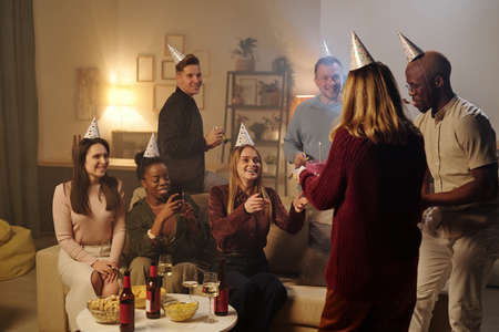 Happy young intercultural friends congratulating smiling girl on her birthdayの写真素材