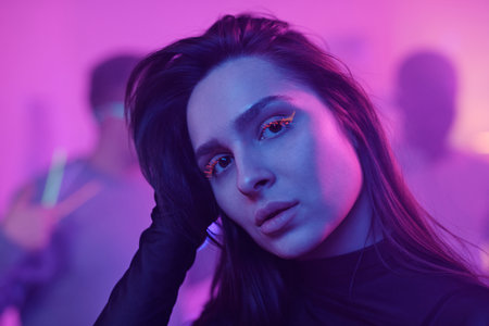 Young glamorous woman with dark long hair in black dress looking at youの写真素材