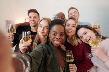 Group of happy young intercultural friends in smart casualwear making selfie