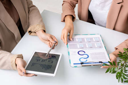 Hands of two young businesswomen analyzing and discussing charts and diagramsの写真素材