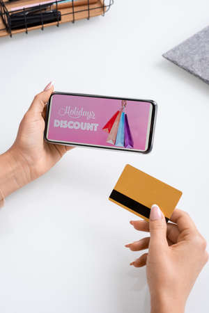 Hands of young contemporary female millennial holding credit card and smartphone
