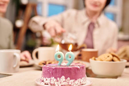 Two burning nine-shaped candles on glazed delicious homemade cake on table