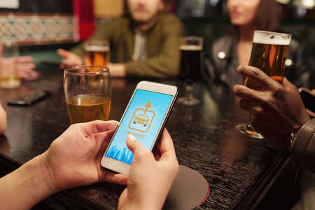 Hand of young woman with smartphone over table going to call for taxi