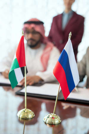 Flags of Russian Federation and United Arab Emirates on table against delegatesの写真素材