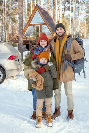 Young affectionate family of three in winterwear standing in front of cameraの写真素材