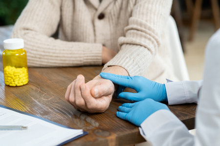Gloved hands of general practitioner in whitecoat touching pulse of sick manの写真素材