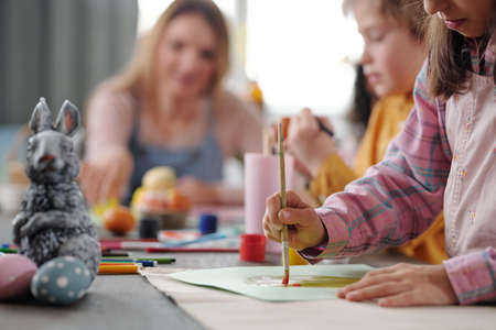 Serious little girl in casualwear painting large Easter egg on paper by tableの写真素材