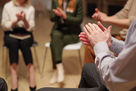 Patients of mental support group clapping hands while sitting in circle during psychological sessionの写真素材