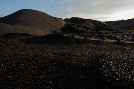 Hills of polluted, infertile and toxic dark soil on vast territory with bad environmental situation with cloudy sky above illustrating desolationの写真素材