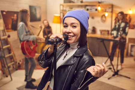 Portrait of young singer smiling at camera while performing on a concert together with her music groupの写真素材