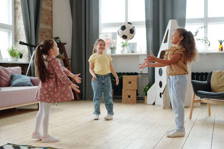 Group of friends playing ball together while standing in the room at home