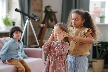 Group of children playing together hide and seek in the room at homeの写真素材