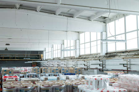 Large warehouse room with canisters and buckets wrapped into polyethylene stacking on each other,...