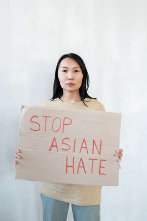 Young woman holding paper announcing protest against Asian hate
