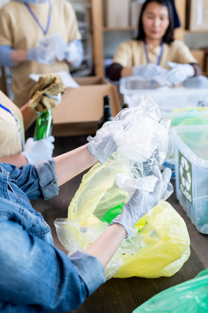 Gloved volunteers working by large tables while recycling trash