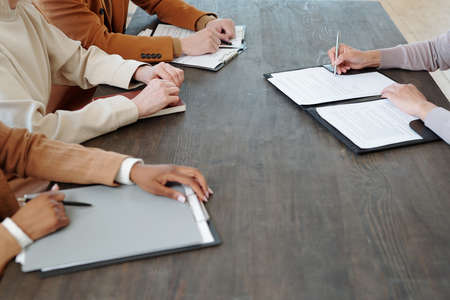 Close-up of unrecognizable candidate sitting at table and signing document while accepting job offer after meeting with recruitersの写真素材