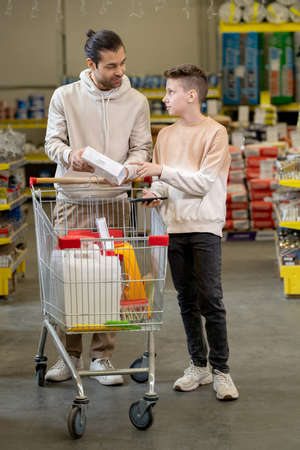 Father and son consulting about household goods while visiting hardware supermarket