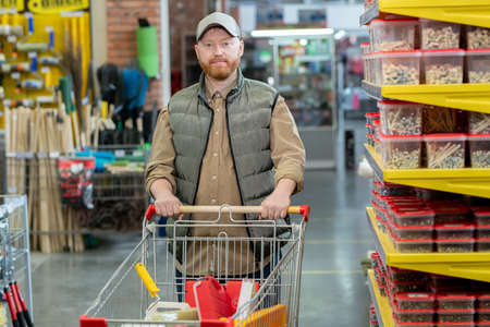Happy middle aged man walking along displays in large modern hardware supermarketの写真素材