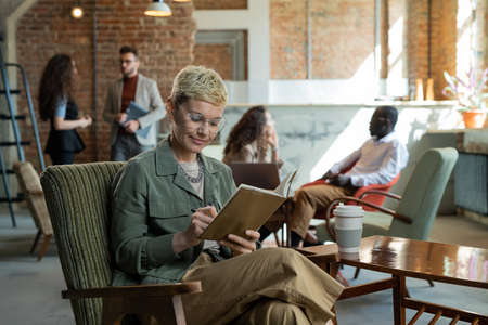 Young businesswoman making notes in notebook in working environmentの写真素材